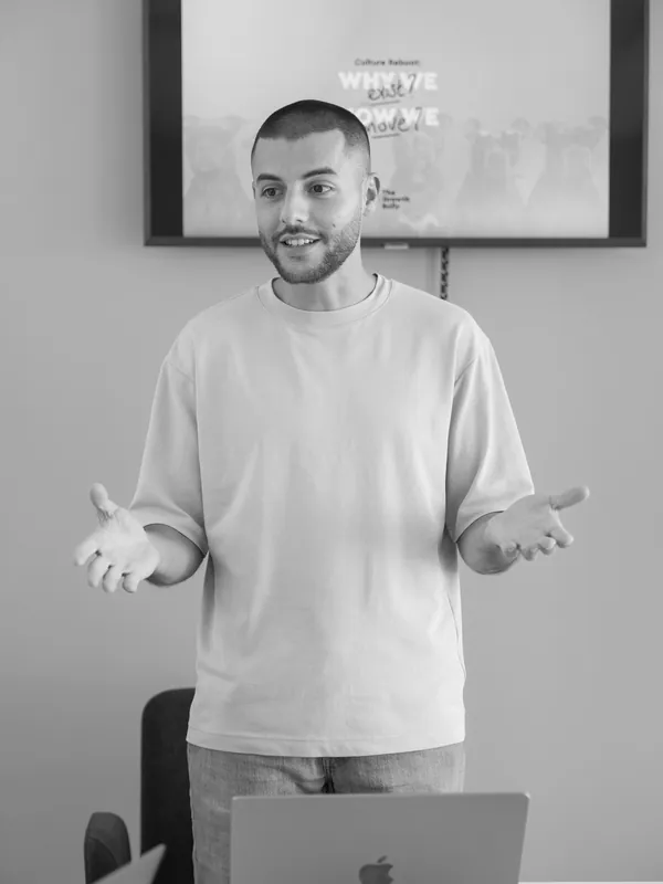 Stephen Ellul presenting to a room, hands open