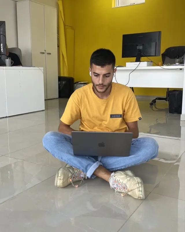 Stephen sitting cross-legged on an office floor with a laptop, October 2022