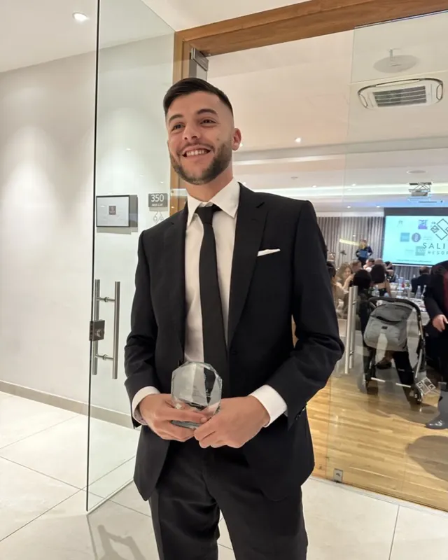Stephen in a black suit holding a glass award at the JCI Malta TOYP night, November 2023