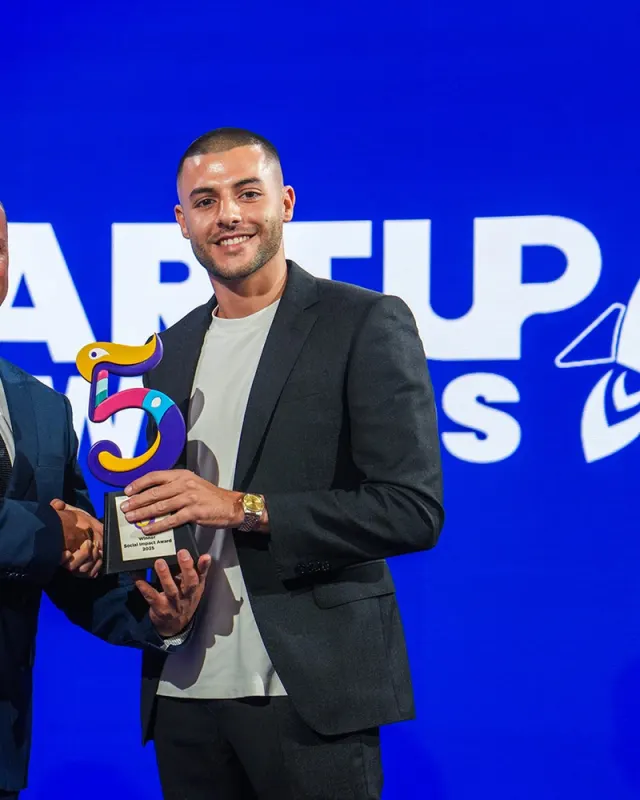 Stephen holding the Social Impact Award on stage at Startup Festival 2025